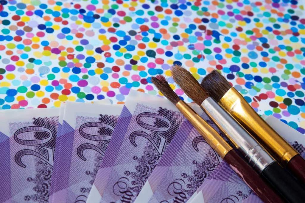 ダミアン・ハーストの作品≪The Currency≫に絵筆と紙幣が重ねられている。