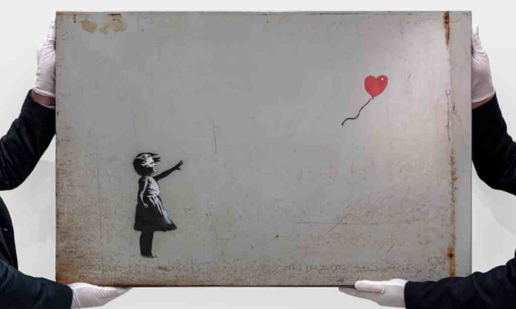 ビー・ウィリアムズから出品される≪Girl with Balloon≫ / バンクシーを2人の人間が持っている　画像引用：https://www.theguardian.com/
